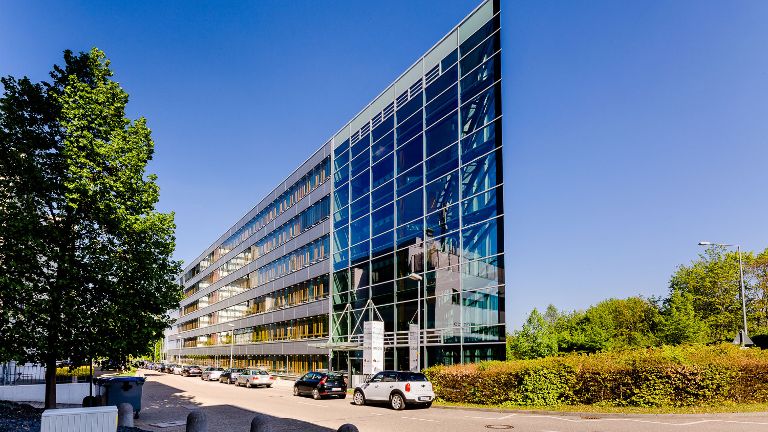 Ein modernes Bürogebäude in Dreiecksform, Blick auf die spitz zulaufende Gebäudeecke aus Glas mit Stahlstreben