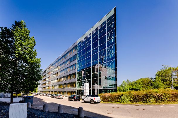 Ein modernes Bürogebäude in Dreiecksform, Blick auf die spitz zulaufende Gebäudeecke aus Glas mit Stahlstreben
